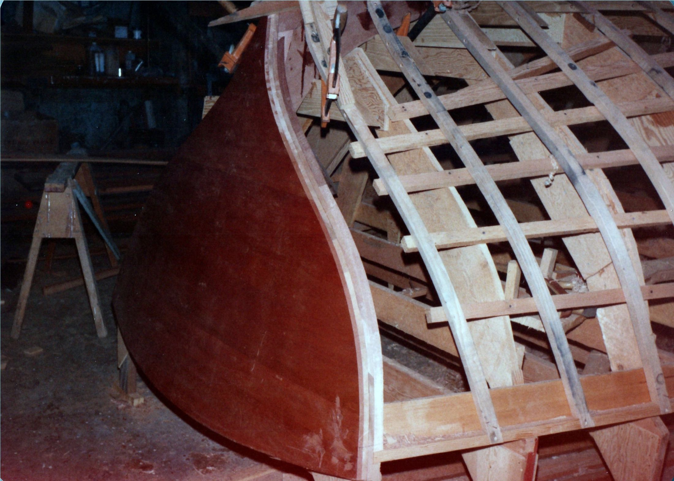 A dark red plywood pattern standing on the shop floor beside the molds