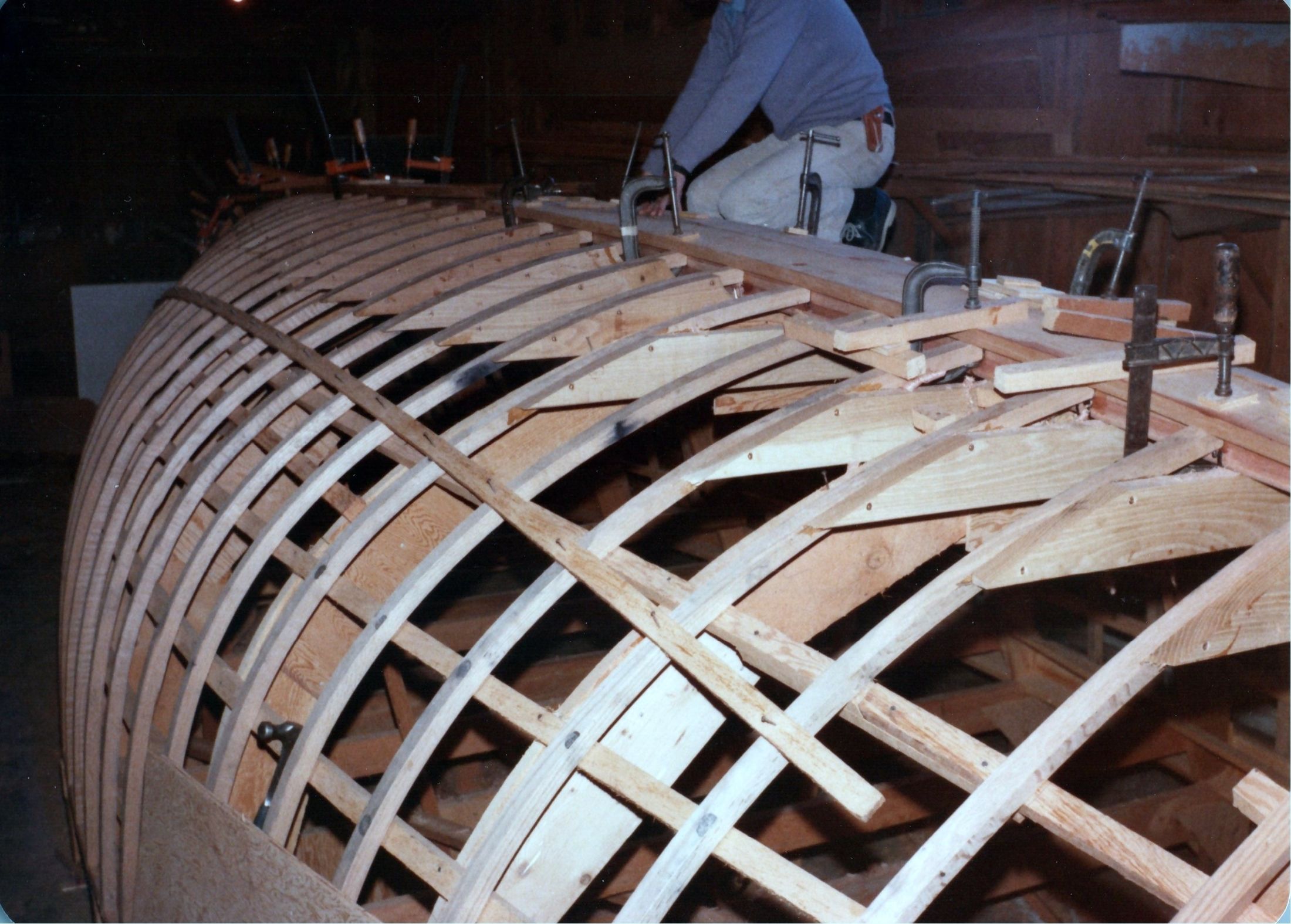 The first planks clamped along the sheer, a man working above
